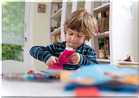 A boy cuts in paper with scissors