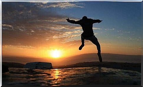 A guy jumps for joy in front of the sunset