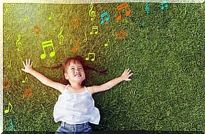 A little girl lying on the grass and listening to music.