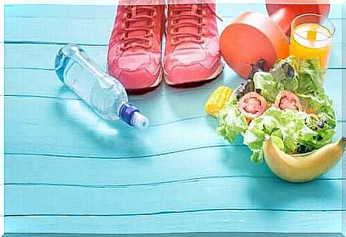 Healthy food, tennis shoes, a dumbbell and a bottle of water on a blue floor