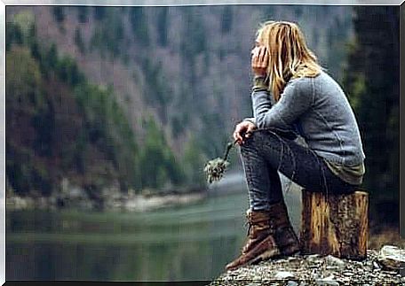 A woman is thinking by the river bank.